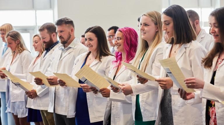 A row of P A students in their white coats recite an oath