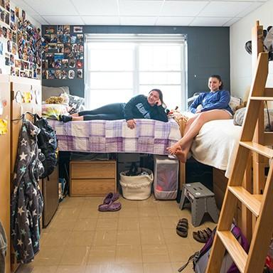 Two UNE Students watching television in their dorm room