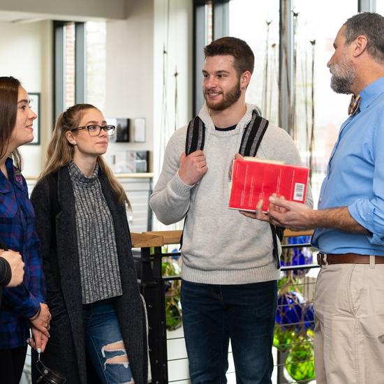A group of students speaking with a professor