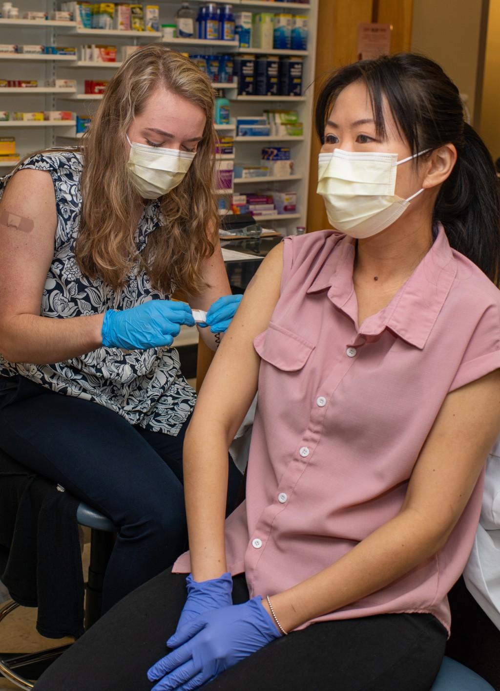 两名药学专业的学生戴着口罩，互相练习在上臂注射疫苗